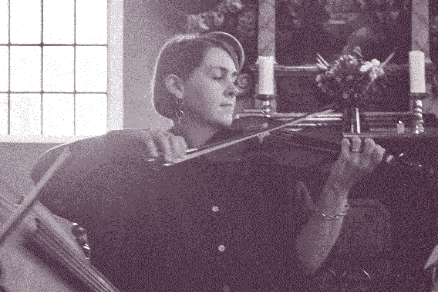 Fotografi på Julija som spelar barockfiol framför altartavlan i en kyrka